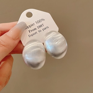 Detail view of large oval silver stud earrings with a brushed satin texture finish