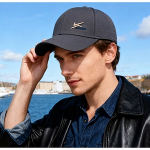 Outdoor close-up of dark grey baseball cap with embroidery against a blue sky background