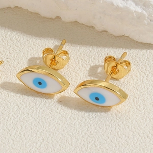 Macro shot of evil eye stud earrings with blue zircon on a textured stone surface