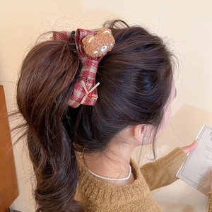 Red plaid bow hair clip with plush bear and heart pendant worn on a brunette hairstyle