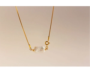 Macro view of white Baroque pearl pendant on a sleek golden snake chain necklace