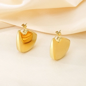 Détail macro de boucles d'oreilles irrégulières plaquées or 18K sur tissu satiné