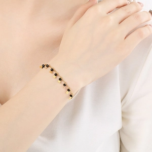 Elegant gold-plated chain bracelet with black beads and dangling petal charms on wrist