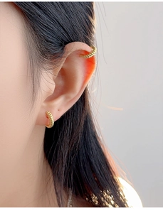 Detailed close-up of golden twisted texture on S925 sterling silver ear cuffs and earrings