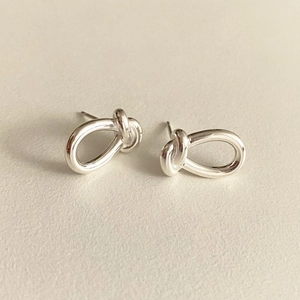 Macro shot of 925 sterling silver knot earrings with polished mirror finish surface