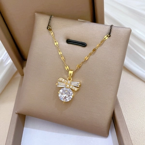 Macro detail of golden butterfly necklace with round cut zircon on silk background