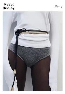 Detail of thin black leather cord belt featuring long gold metal tube accents on waist