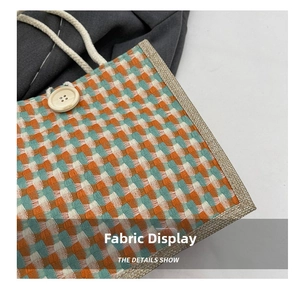 Detailed macro view of woven geometric fabric with orange and teal thread and rope handle