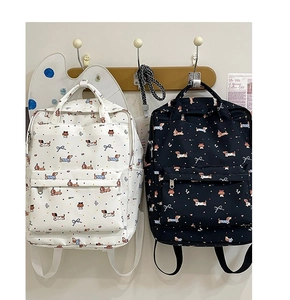 Detail of canvas backpacks featuring dachshund and bow tie prints with front zipper pockets