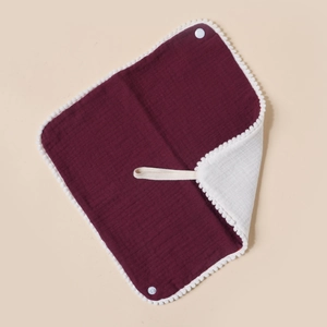 Detailed view of burgundy cotton baby bib with pom-pom trim and snap closure button