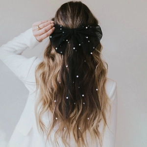 Elegant black mesh bow hair clip with white pearls and long ribbons on female model