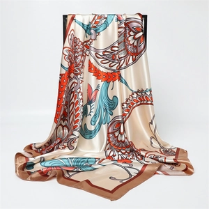 Dettaglio del foulard in raso di seta con motivi paisley arancioni e verde acqua