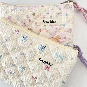Close-up of quilted floral cosmetic bags with cute patterns and woven zipper pulls