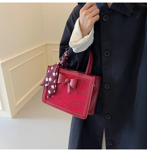 Detail of red bridal handbag with 3D floral lace, bow accent and heart silk scarf