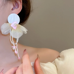 Close-up of model wearing floral pearl tassel earrings with chiffon petals and shell studs