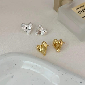 Irregular liquid heart stud earrings in gold and silver finish on elegant display