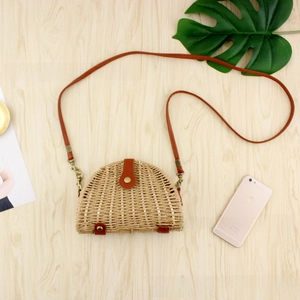 Top view of semi-circular woven paper straw crossbody bag with brown leather accents