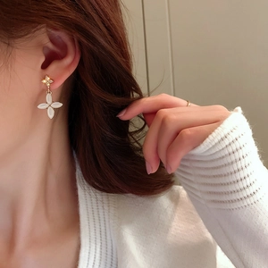 Close-up of elegant opal clover drop earrings with crystal stud on model's ear