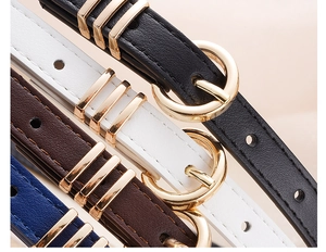 Detail view of four slim faux leather belts in black white brown and blue with gold buckles
