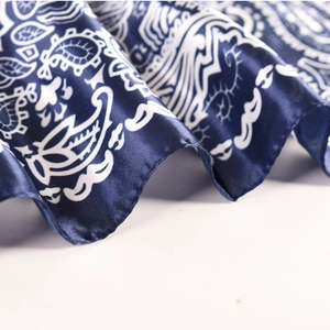 Detailed macro shot of silky dark blue fabric with white paisley print on a satin scarf