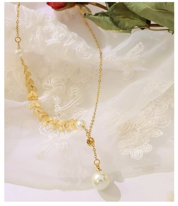 Detail of 18k gold y-necklace featuring laurel leaf metal accents and white pearls