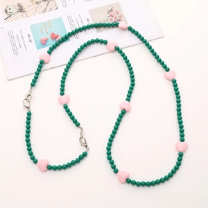 Detail of green acrylic beads and pink heart charms with metal clasps for DIY phone chain
