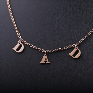 Gros plan des pendentifs DAD en or rose sur un fond de texture en cuir noir