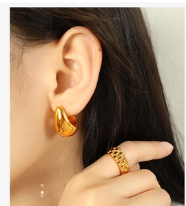 Polished gold drop earrings and chain texture ring shown on a model's side profile