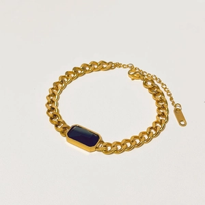 Detail of gold curb chain bracelet with rectangular black gemstone and lobster clasp