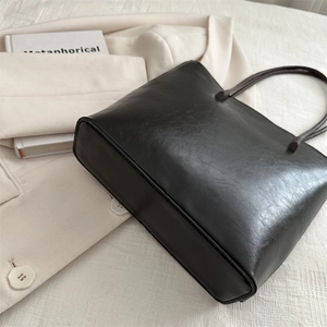 Classic black leather tote bag for women shown from 45-degree angle on blazer background