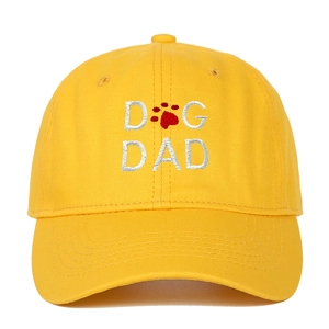 Close-up of yellow cotton baseball cap with white Dog Dad embroidery and red paw print detail