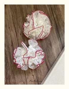 Détail de chouchous en dentelle fleurie avec bords festonnés rouges sur fond bois