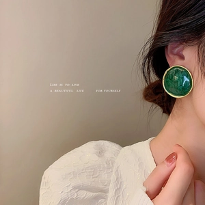 Vintage green enamel stud earrings with gold trim worn by a model in a side profile view