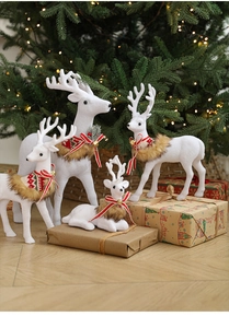 Detail of white flocked reindeer set with bells and scarves for Christmas decor