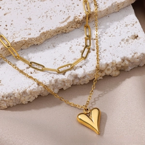 Close-up of gold double-layer necklace with heart pendant on paperclip and fine chain