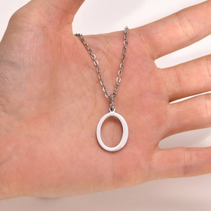 Macro shot of a polished silver stainless steel letter O pendant held in a person's hand