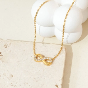 Detail of infinity pendant necklace with zircon stones on white artistic background