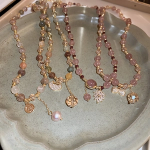 Detailed view of layered freshwater pearl bracelets with leaf and coin charms in a ceramic dish