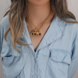 Détail de colliers dorés superposés avec pendentifs en agate bleue, blanche et violette