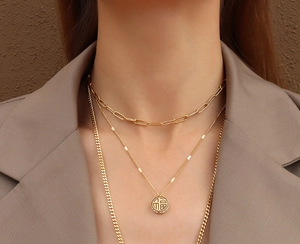 Gros plan sur collier triple épaisseur en or 18 carats avec pendentif Fu et zircons