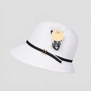 Vista detallada de sombrero de paja blanco con protección UPF 50+ y hebilla dorada
