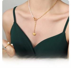 Detail of 18k gold plated titanium steel heart necklace with freshwater pearls on model