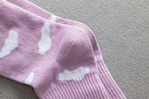 Close-up of purple cotton crew socks featuring white cloud patterns and reinforced heel