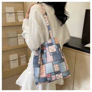 Detail of patchwork denim and pink plaid tote bag shown on model's shoulder in natural light