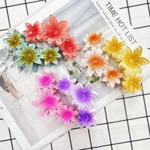 Polished flower hair claws in orange, teal, yellow, and pink on a stylish magazine