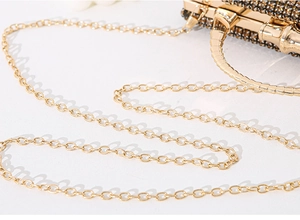 Detailed close-up of the gold metal chain strap and luxury rhinestone clutch bag texture