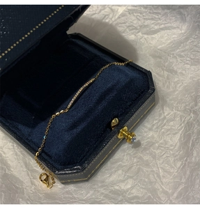 Close-up of gold geometric bracelet with curved diamond bar inlay in a velvet box