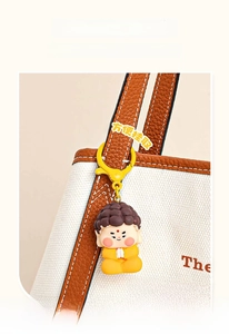 Cartoon Buddha pendant with yellow climbing hook hanging on a stylish canvas bag handle