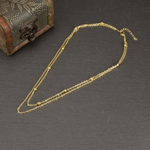 Detail of double-layered gold bead necklace with lobster clasp and adjustable extension chain