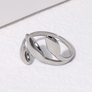 Macro shot of silver adjustable leaf ring in polished titanium steel on textured white surface